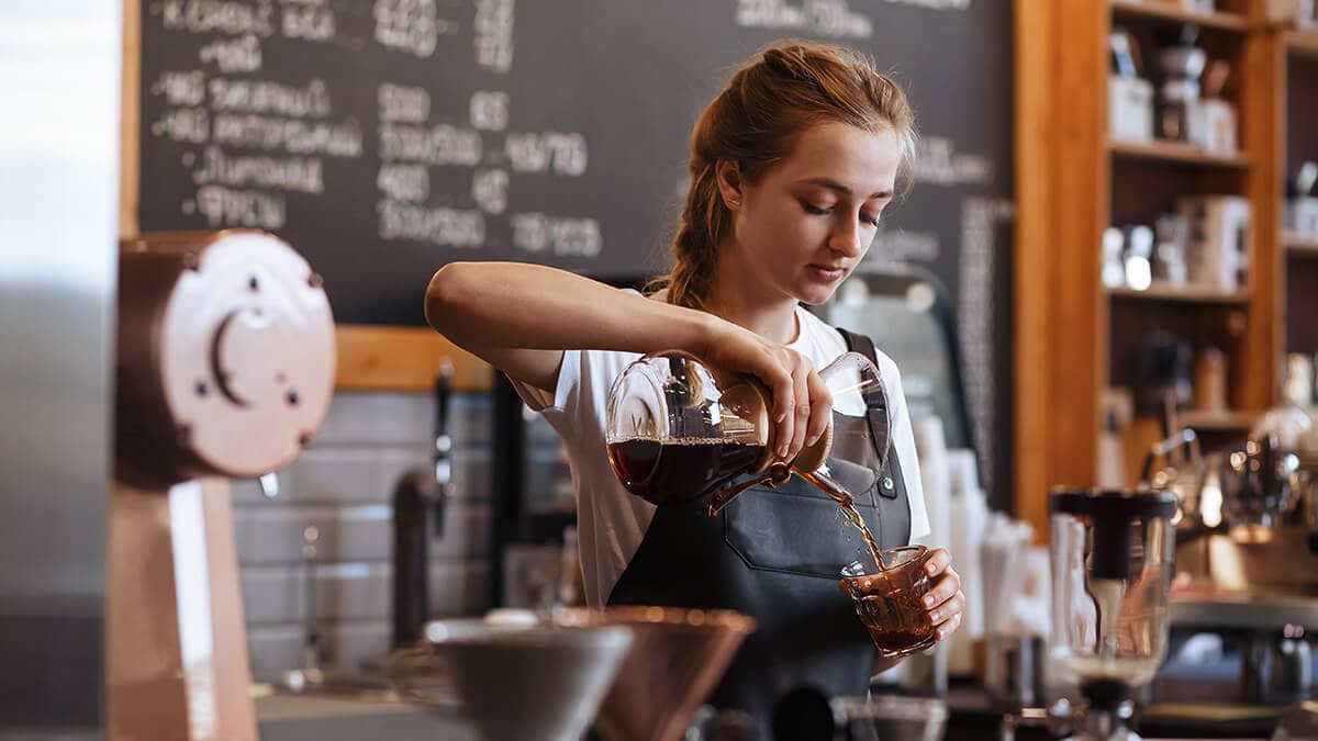 Teenager working as a barista in a coffee shop.