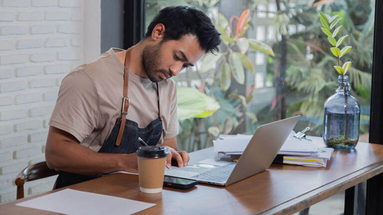 Man in an apron working at his desk.